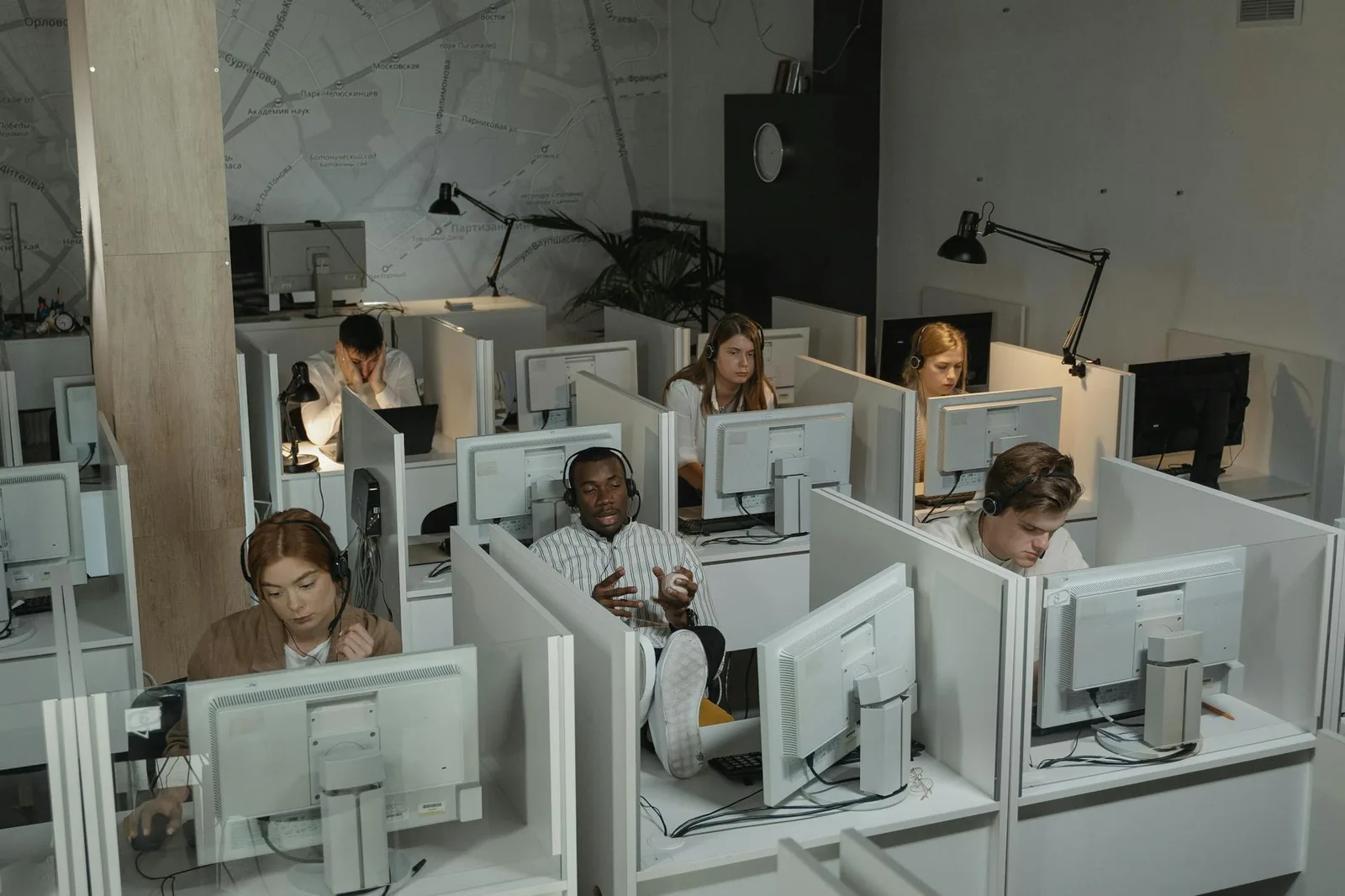 Kiireinen asiakaspalvelutiimi ja puhelinjonoa seuraava dashboard toimistossa.