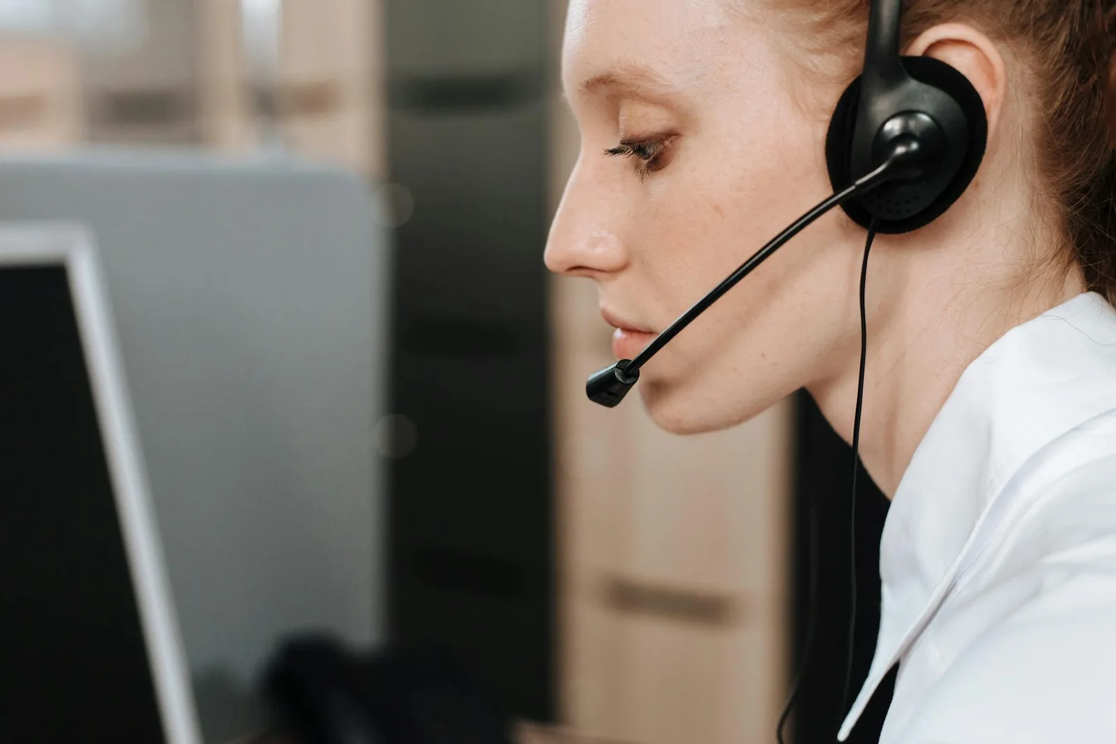 Helpdesk-työntekijä käsittelee tukipuheluita kuulokemikrofonilla